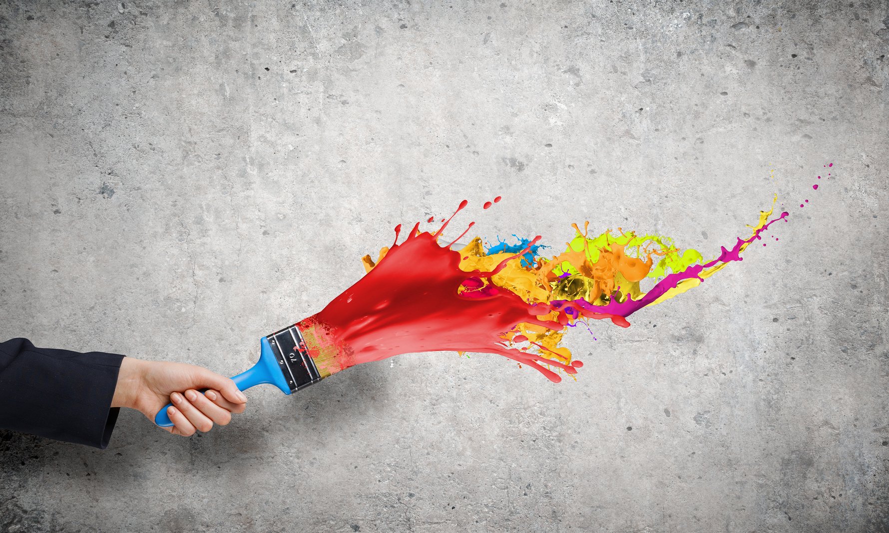 Hand holding a paintbrush with different colors